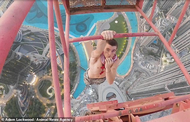 Daredevil climbs to the top of one of Dubai’s tallest buildings and dangles off with one hand