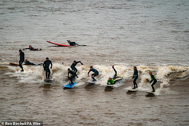 Moment huge line of surfers ride the five-star Severn Bore tidal wave as rare natural phenomenon is seen for in daylight for first time in five years