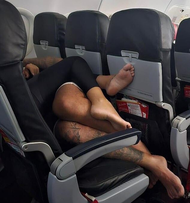 Plane passenger is left horrified by canoodling couple who spent entire four-hour flight SPOONING while lying down across a row of seats BAREFOOT