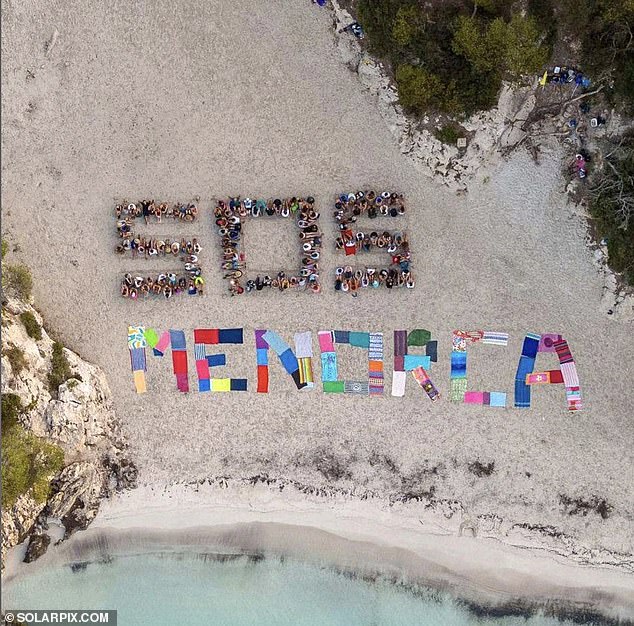 Hundreds of anti-tourism protesters form ‘SOS Menorca’ sign on idyllic beach ‘overrun’ by holidaymakers – after 20,000 took to the streets in Majorca