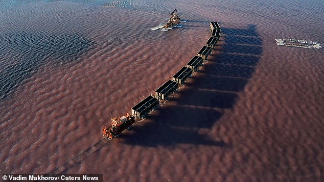 Shore blimey! Stunning drone footage shows a freight train travelling through a LAKE in Siberia